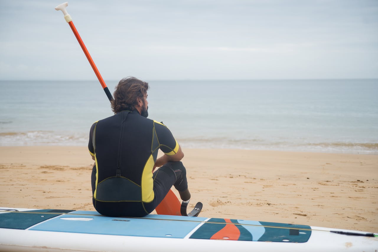 A person sitting on a paddleboard on a beach